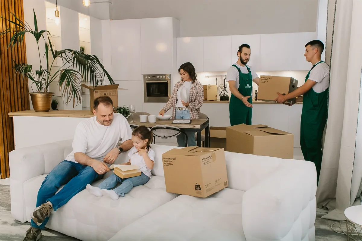 Грузчики выносят коробки, пока семья ждёт отправки вещей